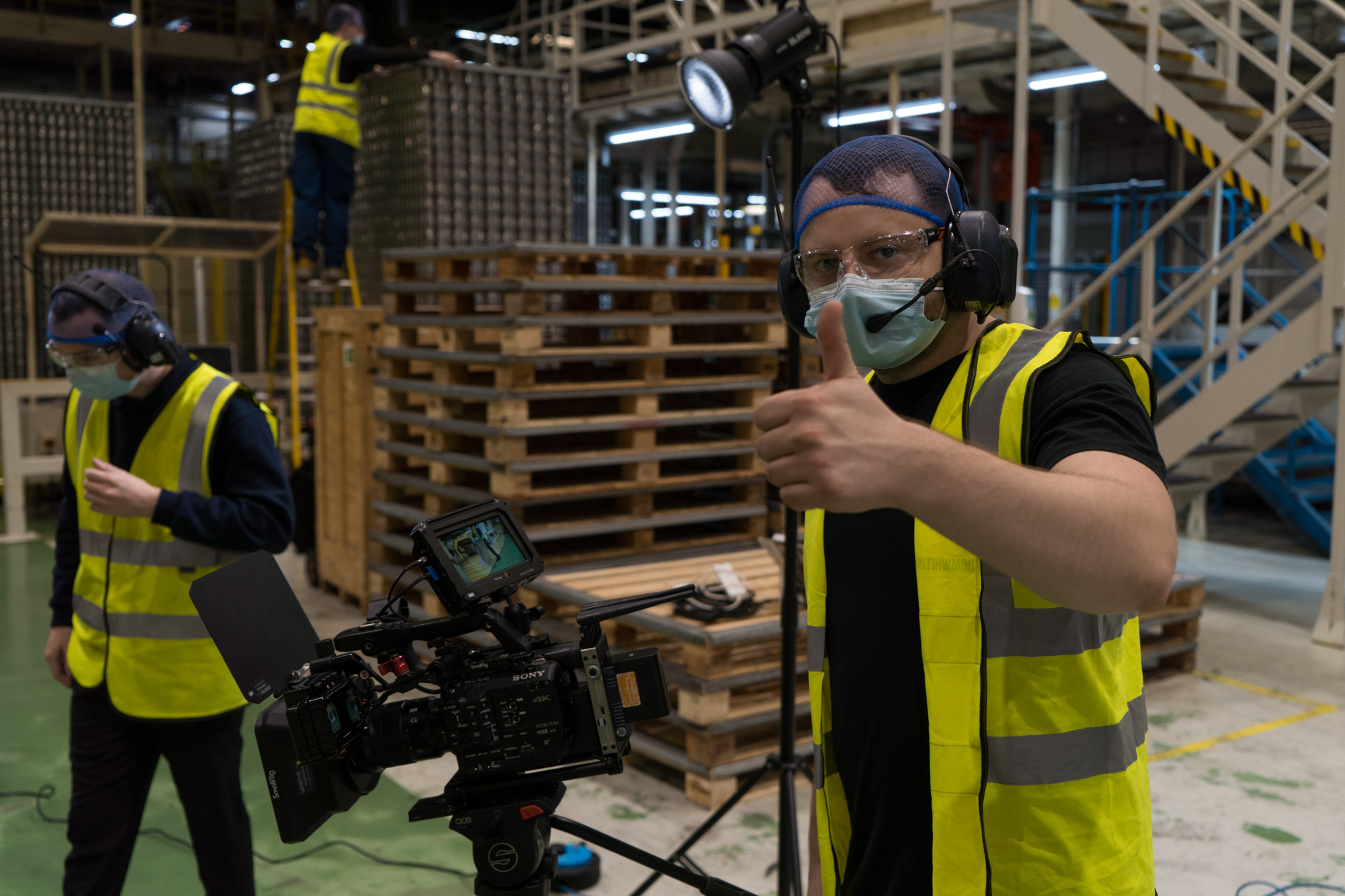 A behind the scenes photo of a member of the videography team giving a thumbs up to camera