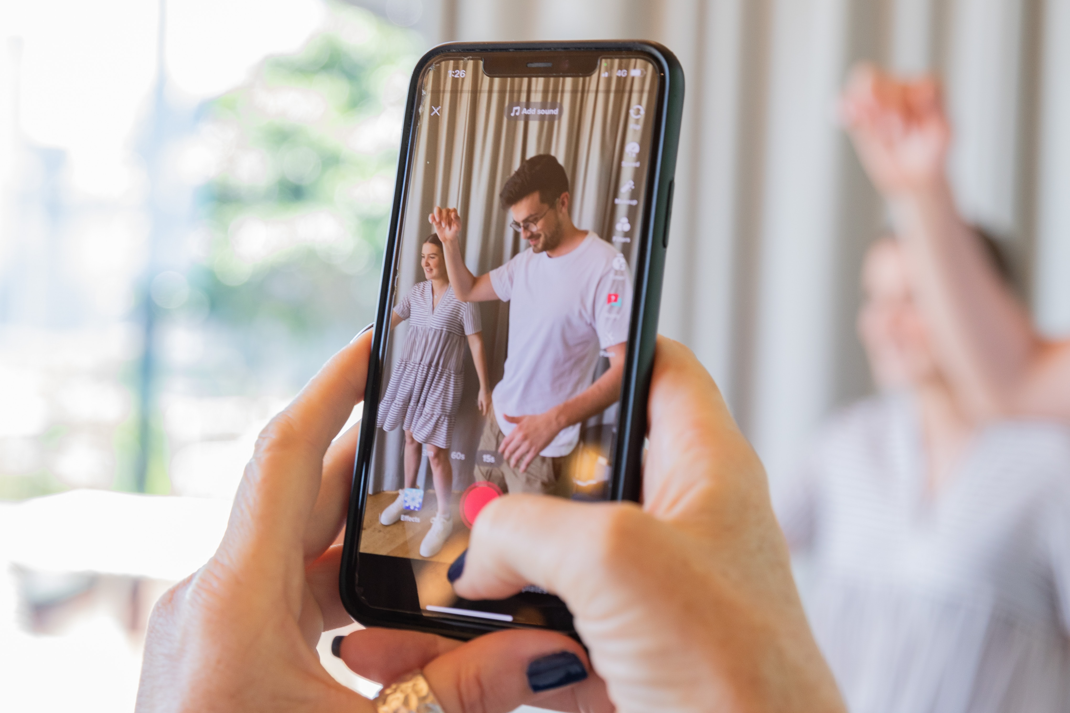 A behind the scenes photo showing a woman recording a video for Instagram reels or TikTok