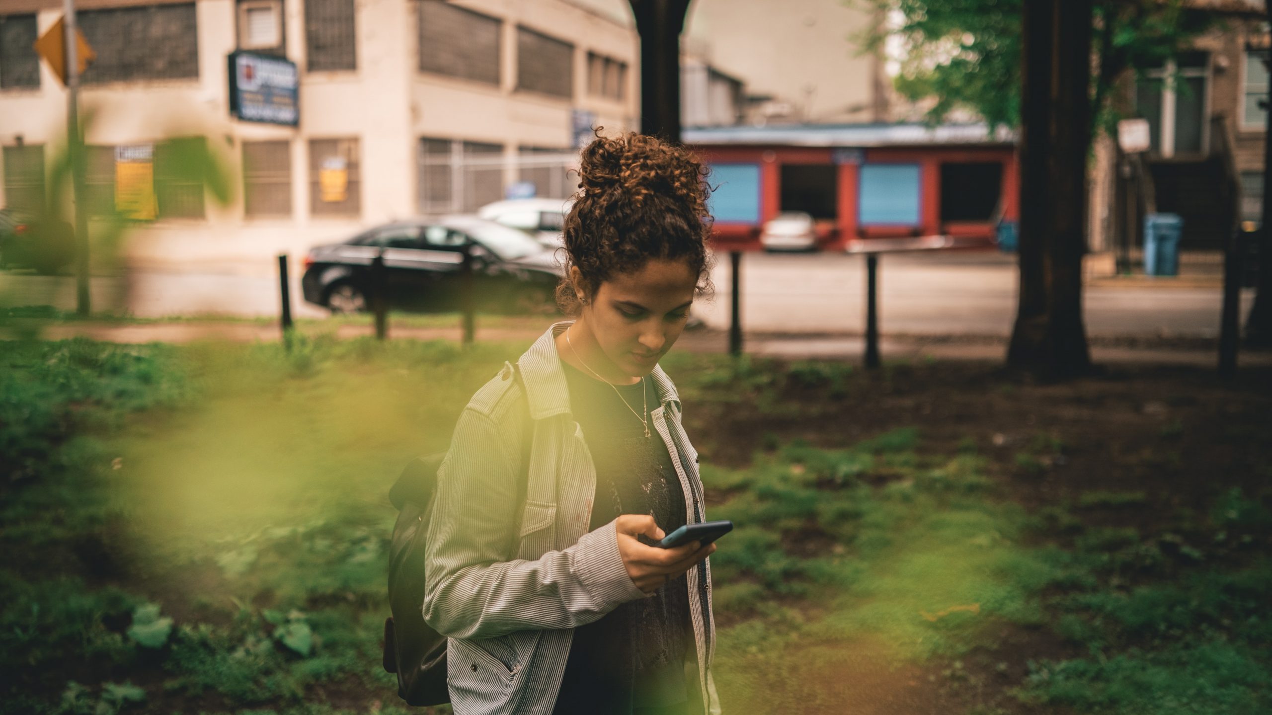 Image shows a generation Z girl outside looking at her phone