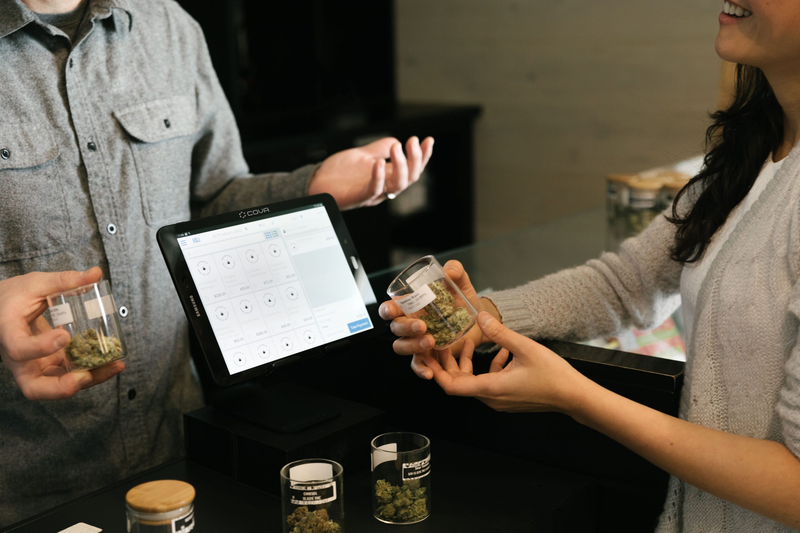 Image shows a transaction happening between a seller and customer. They are both holding the herbal tea product and you can see the till screen between them.