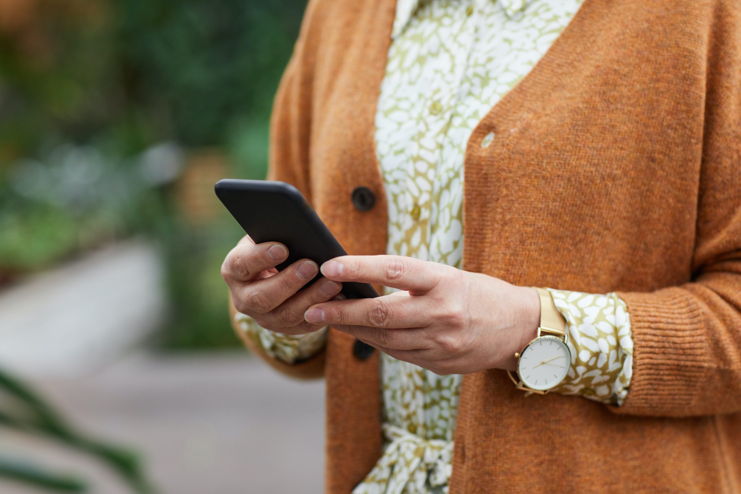 Image shows an older woman's hands holding a mobile phone.