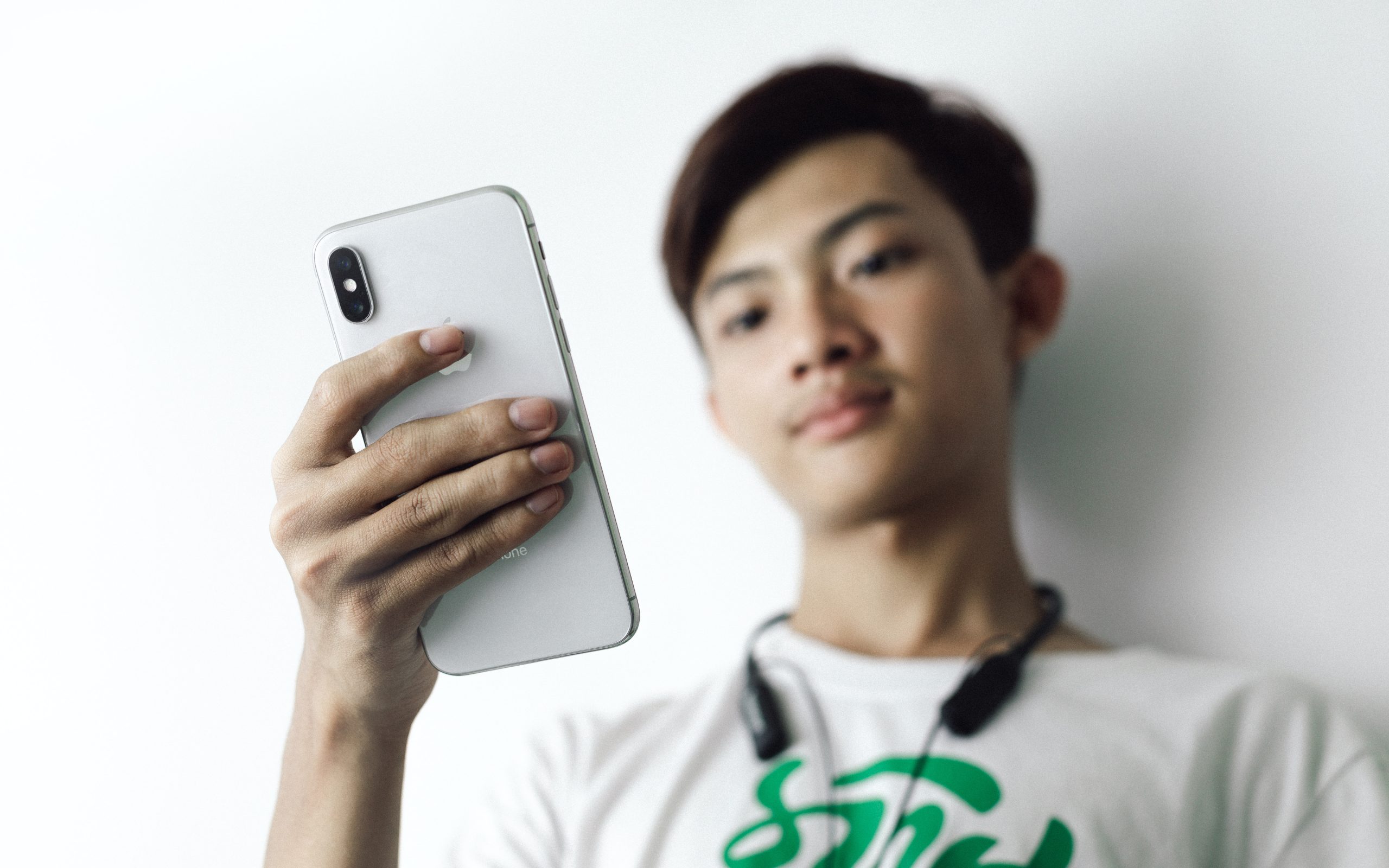 Image shows a young male watching a vide on his mobile phone